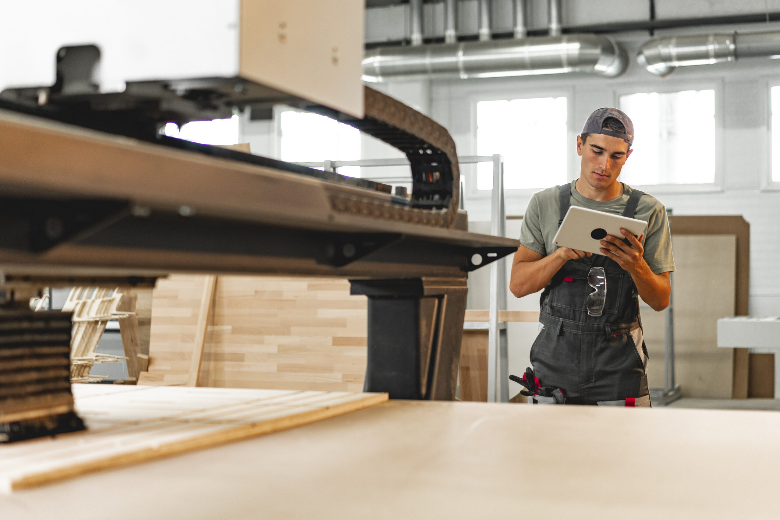 Young carpenter operating machine for wood processing at a furniture factory Young carpenter operating machine for wood processing at a furniture factory